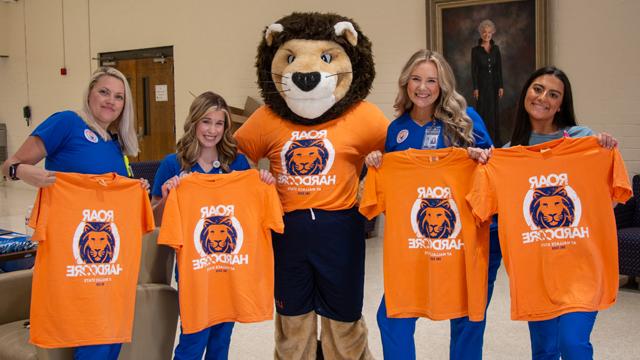 Wallace State mascot and team showing off their Roar shirts